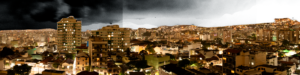 Imagem - Fotografia colorida de paisagem urbana combinada a céu estilizado em tons de cinza.